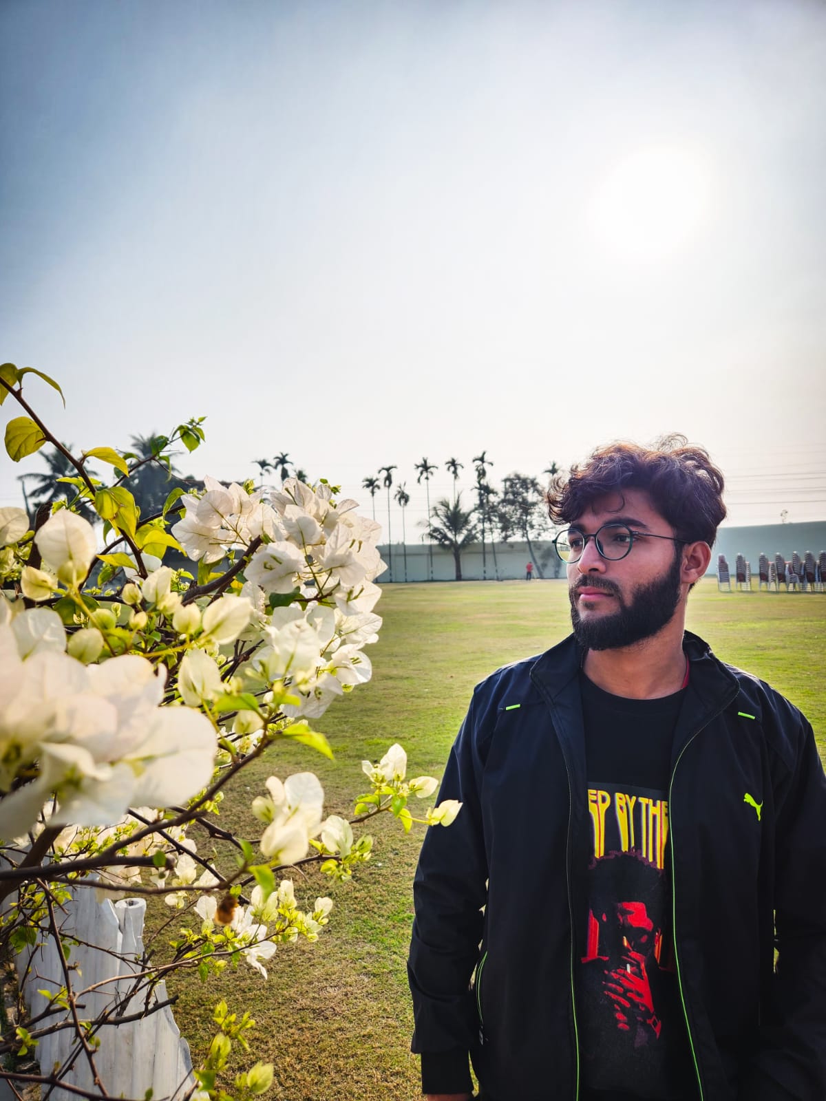 Shobhit in the sun beside white bougainvillea