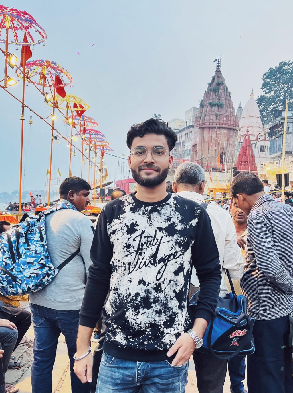 Shobhit at the ghats in Varanasi, temples and festival lights behind